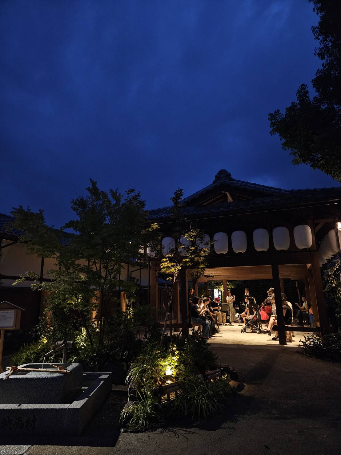 夜の東屋で人が集う映画村の風景